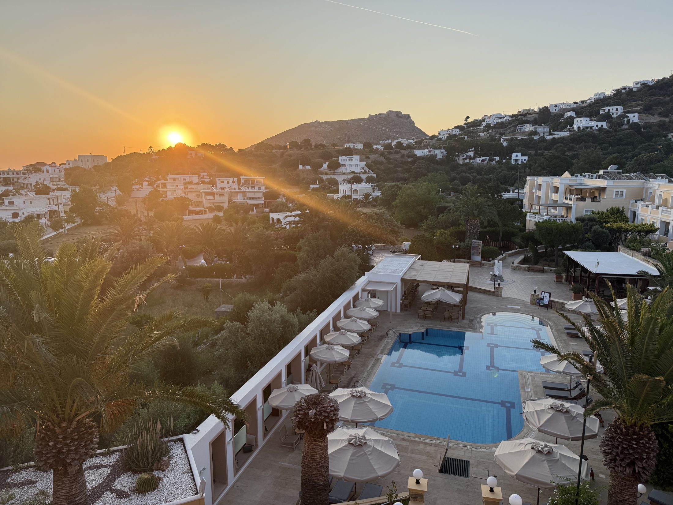 Golden evening light over a Greek island hillside and pool